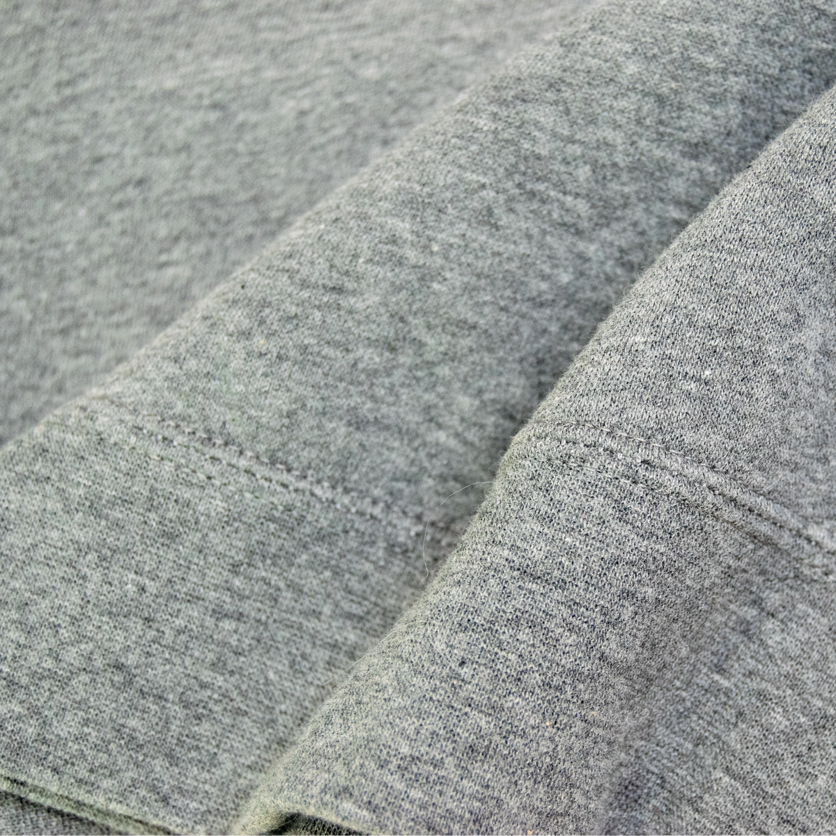 Close-up of a heather gray knit fabric with soft folds and a visible blue accent near the top edge.