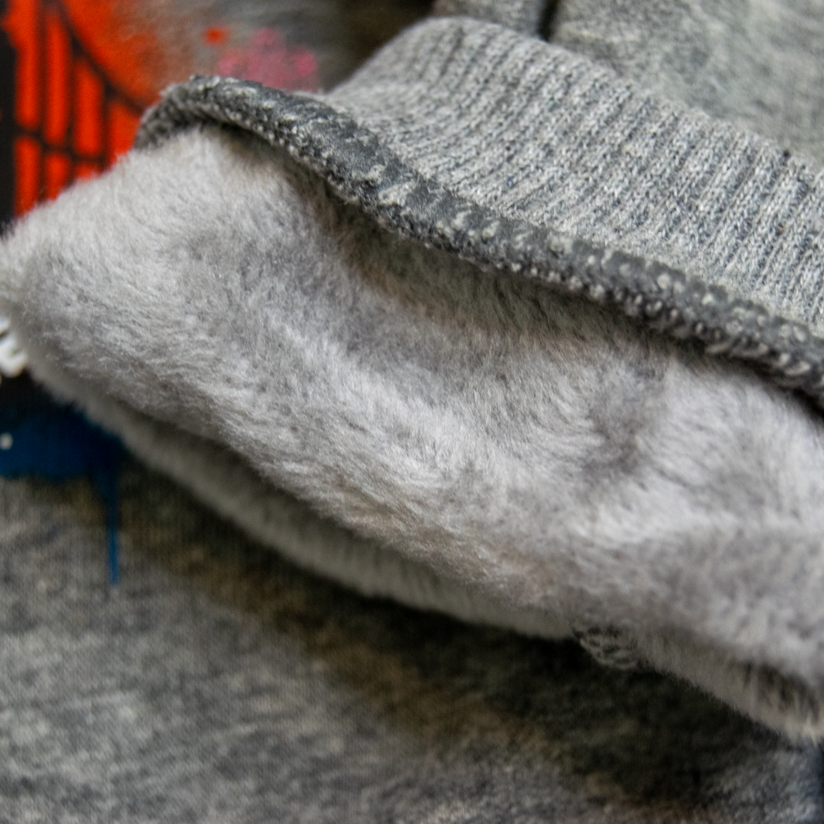 Close-up of a gray knit garment with a soft, fluffy light gray fleece lining folded over.