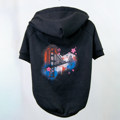 A black pet hoodie shown from the back, featuring a colorful graphic print of the golden gate bridge and pink flowers on the back panel.